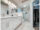 Bathroom with double vanity, white cabinetry, and a glass-enclosed shower with marble-style tiling at 3720 Eversholt St, Clermont, FL 34711