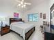 Cozy bedroom showcasing a comfortable bed, a dark wood dresser, and a view to the outside at 3720 Eversholt St, Clermont, FL 34711