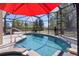 A stunning pool and spa with a red umbrella offer relaxation and shade in a screened-in area at 377 Ed Douglas Rd, Groveland, FL 34736