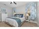 Inviting bedroom featuring a queen bed, plush carpet, and large window with blue patterned curtains at 4256 Fawn Meadows Cir, Clermont, FL 34711