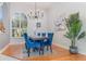 A formal dining room with wood floors, blue chairs, a chandelier, and a large window at 4256 Fawn Meadows Cir, Clermont, FL 34711