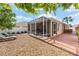 Backyard patio area with tropical landscaping, a screened-in lanai, and lounge seating at 483 Cammarano Pl, The Villages, FL 32162