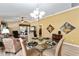 Bright dining area features a round glass table, chandelier, and flows into the living room at 483 Cammarano Pl, The Villages, FL 32162