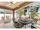 Outdoor screened lanai featuring tile flooring, ceiling fan, and palm trees with a dining set at 483 Cammarano Pl, The Villages, FL 32162