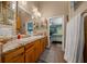 Bright bathroom with granite countertops, double sinks, decorative lighting, and access to the main bedroom at 4940 County Road 134B, Wildwood, FL 34785