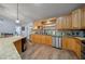 Kitchen with wooden cabinets and granite countertops, featuring stainless steel appliances and views to other rooms at 4940 County Road 134B, Wildwood, FL 34785