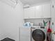 This well-equipped laundry room includes a modern washer, dryer, and ample storage in the upper cabinets at 5533 Squires Dr, Leesburg, FL 34748