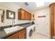 Laundry room with wood cabinets, gray countertop, utility sink, and modern washer and dryer units at 589 Society Hill Cir, The Villages, FL 32162