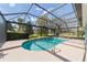 Beautiful screened-in pool area with a water feature and a view of the lush green landscaping and golf course at 589 Society Hill Cir, The Villages, FL 32162