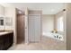 Bright bathroom features a large bathtub, walk-in shower, and dark wooden vanity at 5890 Sw 167Th Pl, Ocala, FL 34473