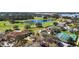 An aerial view showcases a beautiful golf course, lake, clubhouse, tennis courts, and pool at 6035 Falconbridge Pl, Mount Dora, FL 32757