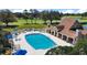 Aerial view of a large community pool with lounge chairs, umbrellas, and a clubhouse nearby at 6035 Falconbridge Pl, Mount Dora, FL 32757