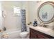 Well-lit bathroom with a large round mirror, decorative shower curtain, and granite countertops at 6342 Sailboat Ave, Tavares, FL 32778