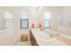 Bright bathroom featuring double sinks, large mirror, and white tile shower with natural light from the window at 9188 Chandler Dr, Groveland, FL 34736