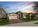 Beautiful single-Gathering home boasting stone accents, a two-car garage, and brick driveway at sunset at 9188 Chandler Dr, Groveland, FL 34736