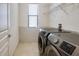 Functional laundry room equipped with a modern washer and dryer, shelving, and tile flooring at 9188 Chandler Dr, Groveland, FL 34736