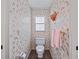 Small bathroom featuring charming butterfly wallpaper, a toilet, and a towel rack at 9829 Wedgewood Ln, Leesburg, FL 34788