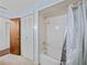 Well-lit bathroom featuring a shower-tub combo with tile surround and a linen closet at 9829 Wedgewood Ln, Leesburg, FL 34788