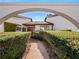 Inviting front entrance framed by a unique archway and lush, green hedges on either side at 9829 Wedgewood Ln, Leesburg, FL 34788