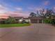 A spacious home featuring a three-car garage, mature landscaping, and a large, paved driveway at 9829 Wedgewood Ln, Leesburg, FL 34788