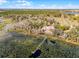 Aerial view of the home and property near a lily pad covered lake at 10944 Autumn Ln, Clermont, FL 34711