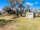 Wide angle showcasing the green metal shed and large red barn with surrounding greenery at 10944 Autumn Ln, Clermont, FL 34711