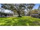 Lush backyard with mature trees offering shade, leading to waterfront with a boat dock and patio at 11136 Bronson Rd, Clermont, FL 34711