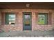 Close up of a brick front porch with a front door and windows with dark shutters at 12320 Blue Heron Way, Leesburg, FL 34788