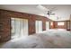 Bright living room featuring brick walls, plush carpeting, and multiple ceiling fans at 12320 Blue Heron Way, Leesburg, FL 34788