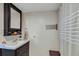 This is a bathroom with cream walls, a dark sink vanity and a mirror with storage. The shower has a white curtain at 1236 Selman Rd, Leesburg, FL 34748