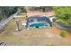 Aerial view of a screened-in pool and spa with a spacious backyard with mature trees at 1236 Selman Rd, Leesburg, FL 34748