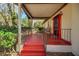 Inviting front porch with a red painted floor and ceiling, a metal railing, and a rocking chair at 1236 Selman Rd, Leesburg, FL 34748