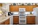 Kitchen featuring wooden cabinets, white appliances, and decorative dishware on top of cabinets at 12497 Se 92Nd Ave, Summerfield, FL 34491