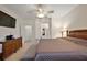 Main bedroom with ceiling fan, dresser, TV, and attached bathroom at 12497 Se 92Nd Ave, Summerfield, FL 34491