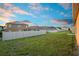 Expansive green backyard enclosed by a pristine white fence under a partly cloudy sky for enhanced privacy at 125 Sunny Day Way, Davenport, FL 33897