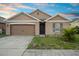 Inviting single-Gathering home with a brown two-car garage, trimmed lawn, and clean driveway at 125 Sunny Day Way, Davenport, FL 33897