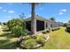 A view of the rear of the property and screened lanai with surrounding shrubs and trees at 1357 Owl Dr, The Villages, FL 32163