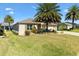 Well-maintained home featuring lush green lawn, palm trees, and tasteful landscaping at 1357 Owl Dr, The Villages, FL 32163