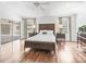 Virtually staged main bedroom featuring hardwood floors, dresser, lamps, and a picturesque view at 164 Palermo Pl, The Villages, FL 32159