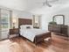 Virtually staged main bedroom featuring hardwood floors, dresser, lamps and a picturesque view at 164 Palermo Pl, The Villages, FL 32159