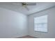 Simple bedroom with light-colored floor, white walls, ceiling fan and a large window at 1671 Campos Dr, The Villages, FL 32162