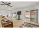 A living room with sliding glass doors, tan carpet, ceiling fan and adjacent seating area at 1841 Dunn Cove Dr, Apopka, FL 32703