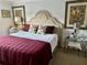 Serene main bedroom featuring a tufted headboard, plush bedding, mirrored nightstands, and tasteful artwork at 2427 Tamarind Grove Run, The Villages, FL 32162