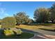 Charming street view featuring manicured lawns, mature trees, and a lovely gazebo in the distance at 2427 Tamarind Grove Run, The Villages, FL 32162