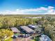 Aerial view of a boat dock, beautiful trees and foliage, and a body of water, underneath a partly cloudy sky at 3221 Myakka River Rd, Tavares, FL 32778