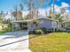 Exterior elevation of charming blue house with well-manicured lawn, driveway, and carport at 3221 Myakka River Rd, Tavares, FL 32778