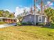 Single Gathering home featuring lawn, tropical landscaping, and hardscaped flower bed at 3221 Myakka River Rd, Tavares, FL 32778