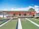 This image displays a shuffleboard court with shade structure in the foreground with pool and clubhouse behind at 3221 Myakka River Rd, Tavares, FL 32778