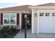 Close-up of house entrance with decorative lamp post, window with shutters, and a three-car garage door at 3290 Sennett Cir, Oxford, FL 34484