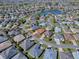 Aerial view of a community neighborhood and single Gathering home featuring mature landscaping and a neighborhood lake at 3330 Mayflower Loop, The Villages, FL 32163